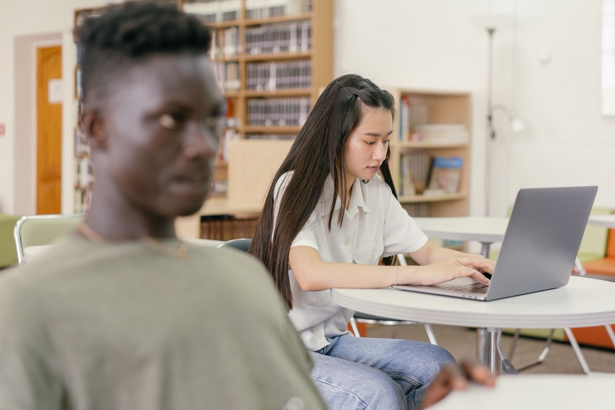Students working on a laptop in a library